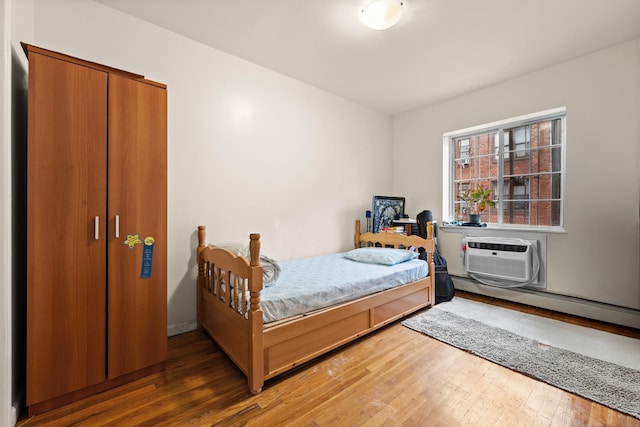 bedroom with dark hardwood / wood-style floors, a baseboard heating unit, and a wall mounted AC