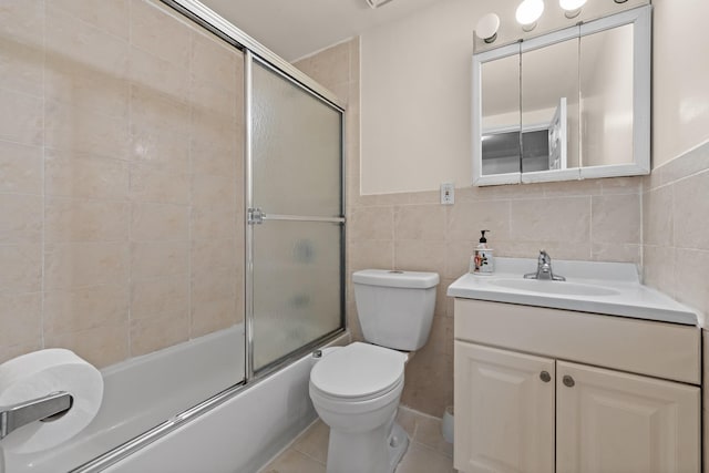 full bathroom with shower / bath combination with glass door, vanity, tile walls, and toilet