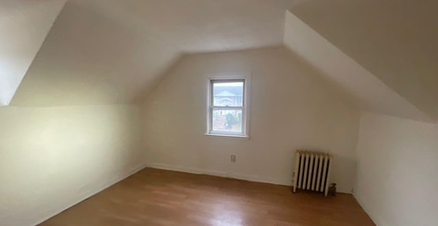 additional living space featuring radiator heating unit, hardwood / wood-style floors, and lofted ceiling