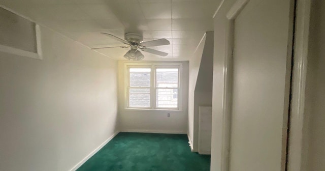 empty room featuring ceiling fan and dark carpet