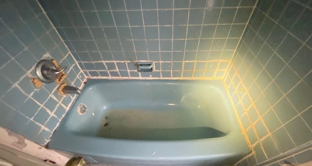 bathroom featuring tile walls and a tub