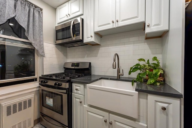 kitchen featuring appliances with stainless steel finishes, tasteful backsplash, radiator, sink, and white cabinets