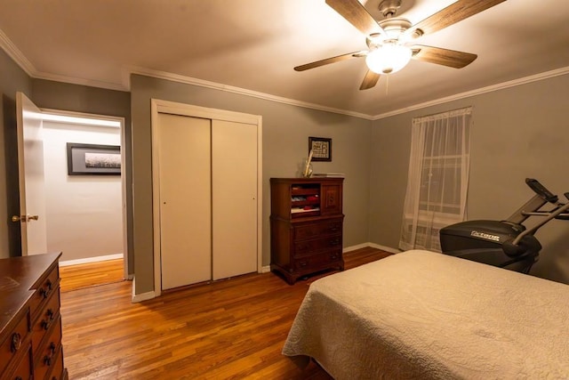 bedroom with ceiling fan, wood-type flooring, ornamental molding, and a closet