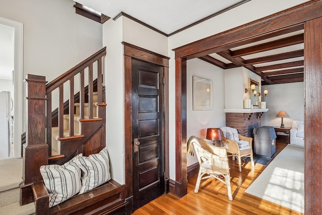 interior space with hardwood / wood-style floors, a fireplace, ornamental molding, and beamed ceiling