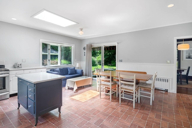 kitchen with blue cabinets, a kitchen island, electric stove, radiator heating unit, and white cabinetry