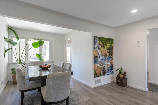 dining area featuring ornamental molding and light hardwood / wood-style floors