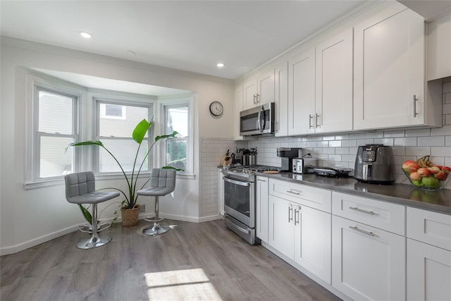 kitchen featuring white cabinetry, stainless steel appliances, decorative backsplash, and light wood-type flooring