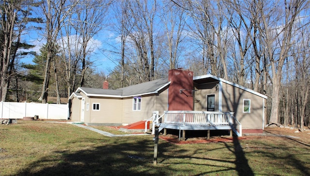 rear view of house with a lawn and a wooden deck