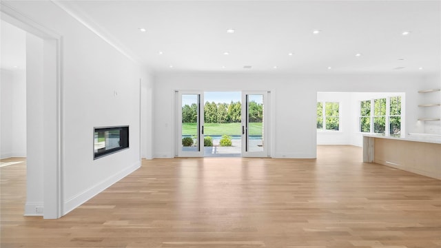 unfurnished living room featuring light hardwood / wood-style flooring and ornamental molding