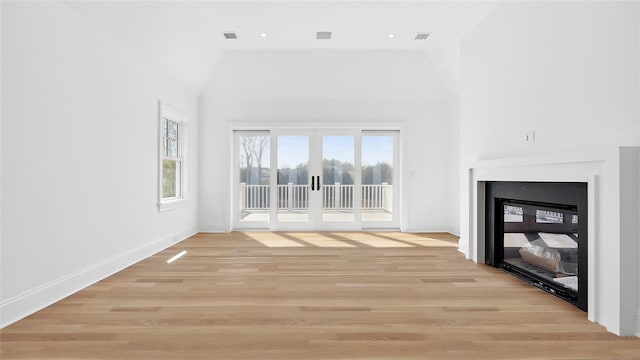 unfurnished living room featuring light hardwood / wood-style floors, high vaulted ceiling, and french doors