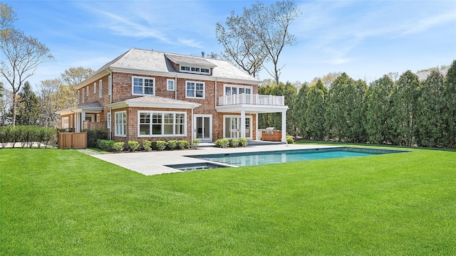 rear view of house with a patio area, a balcony, and a yard