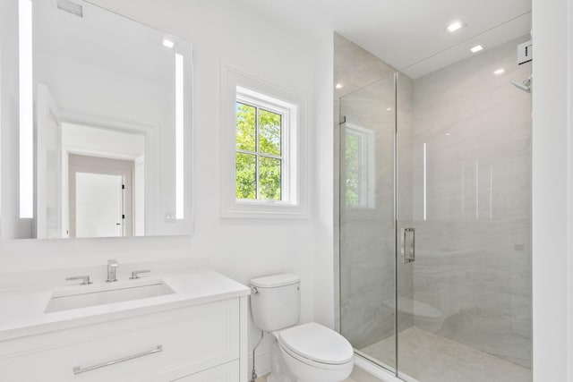 bathroom featuring a shower with door, vanity, and toilet