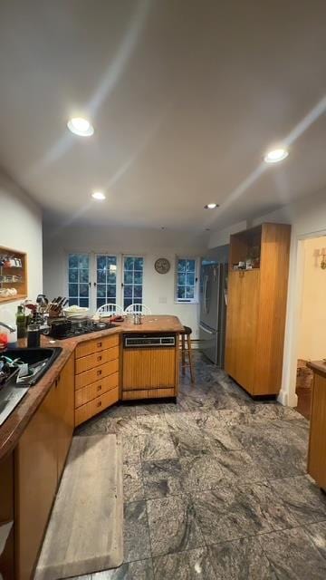 kitchen featuring dishwashing machine, kitchen peninsula, and stainless steel refrigerator