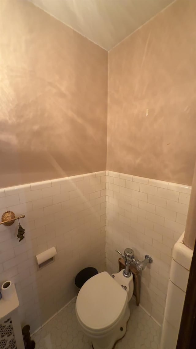 bathroom with tile patterned flooring, tile walls, and toilet