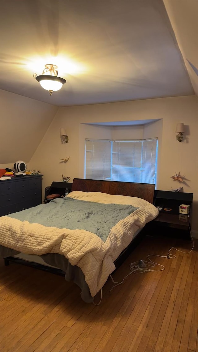 bedroom with hardwood / wood-style floors and lofted ceiling