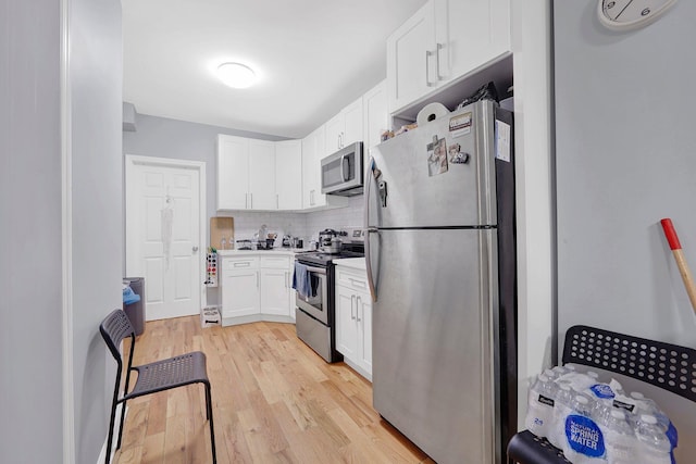 kitchen featuring backsplash, stainless steel appliances, white cabinetry, and light hardwood / wood-style flooring