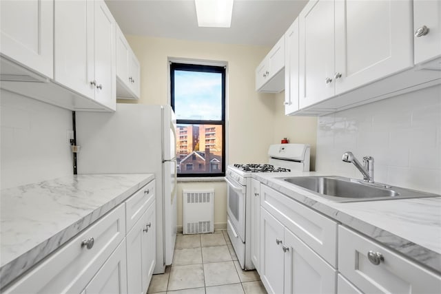 kitchen featuring light tile patterned floors, white appliances, white cabinetry, and sink