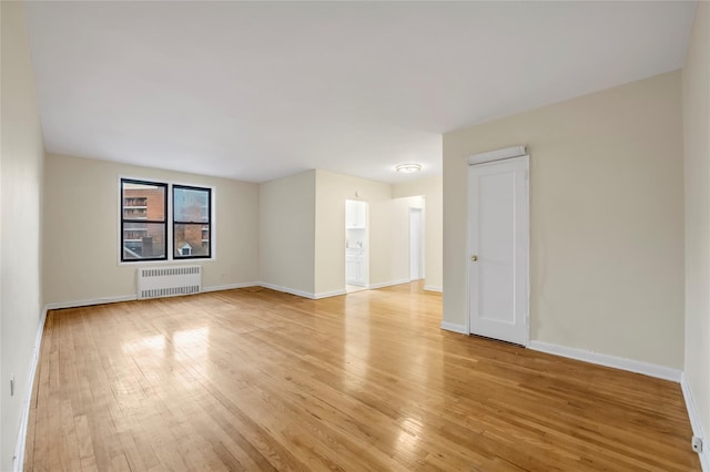 spare room featuring radiator heating unit and light hardwood / wood-style flooring