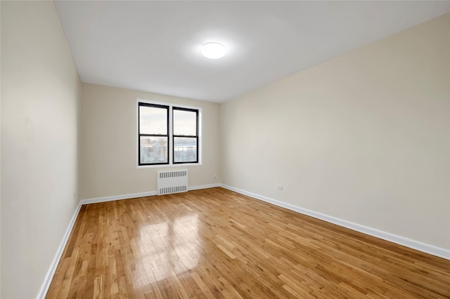 unfurnished room featuring light hardwood / wood-style floors and radiator heating unit