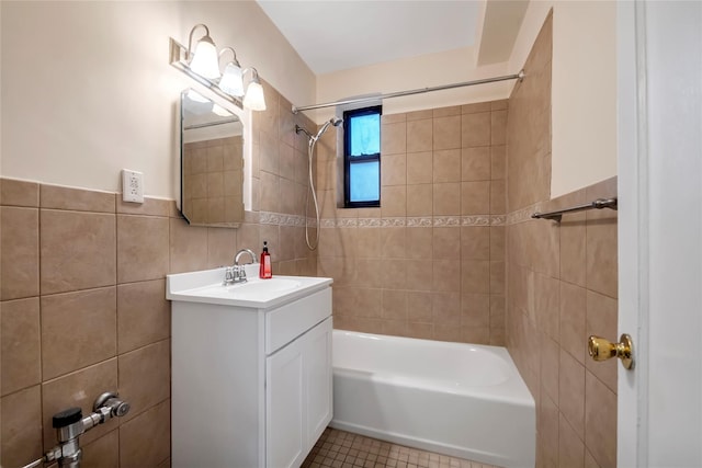 bathroom with tile patterned flooring, vanity, tiled shower / bath combo, and tile walls