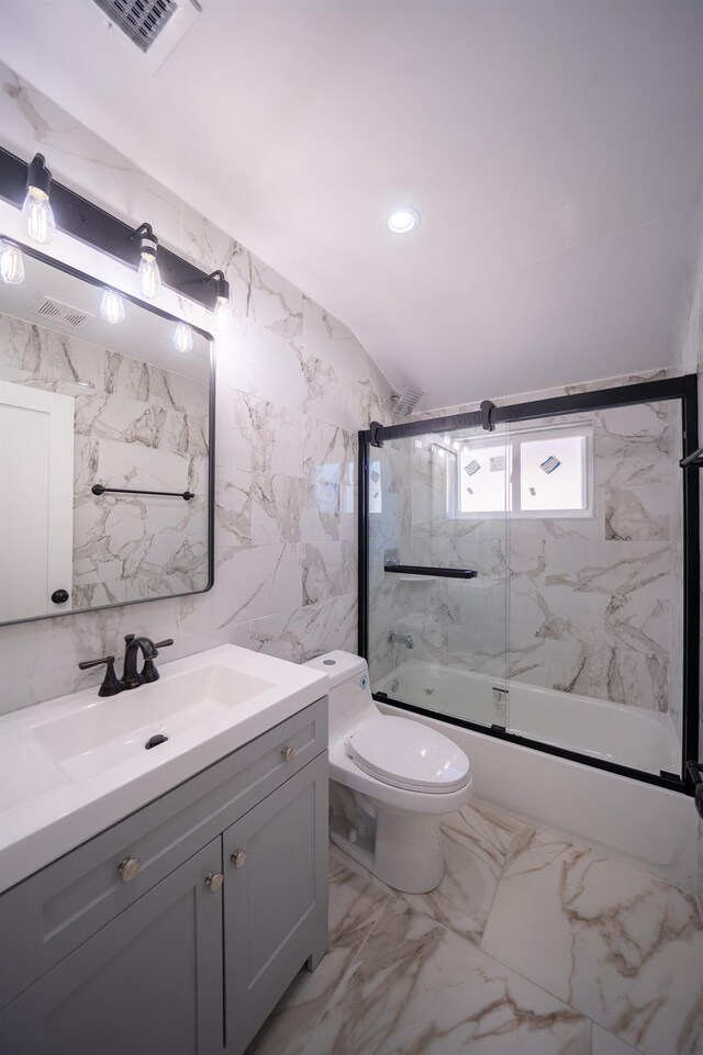 115-42 Inwood St, Jamaica, NY 11436 - bathroom with bath / shower combo with glass door, vanity, toilet, marble finish floors, and tile walls
