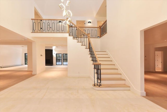 stairway with carpet, a high ceiling, and a baseboard heating unit