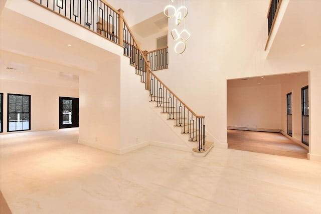 staircase featuring a baseboard heating unit, a towering ceiling, and french doors