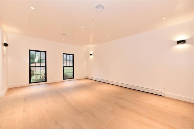 empty room featuring light hardwood / wood-style flooring and a baseboard heating unit