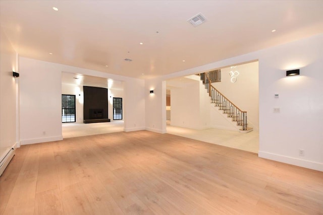 unfurnished living room featuring a large fireplace and light hardwood / wood-style flooring