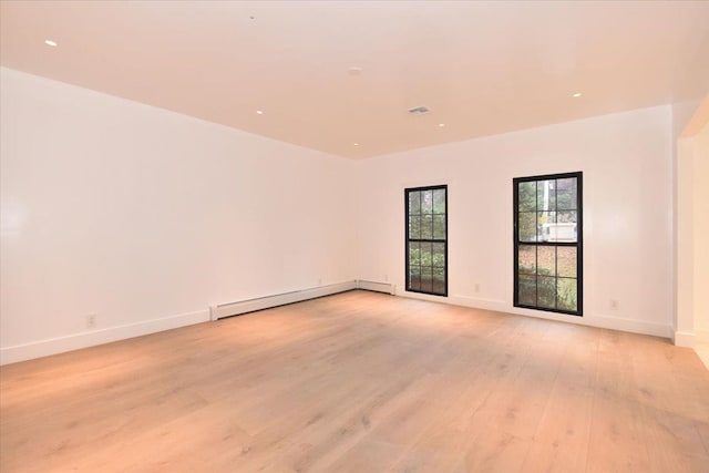 unfurnished room featuring light hardwood / wood-style floors and a baseboard heating unit