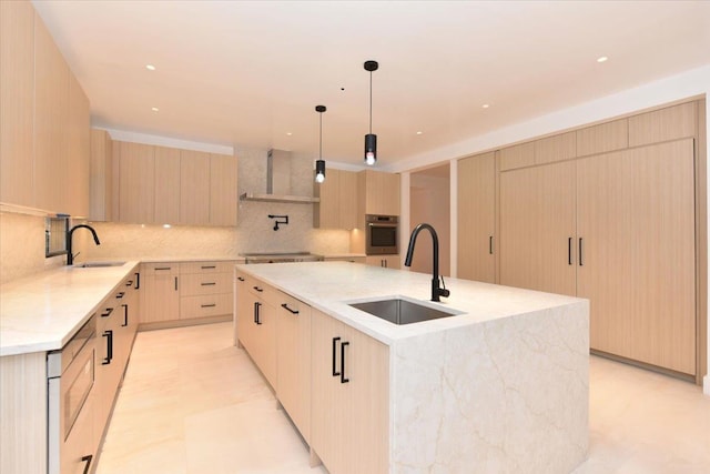 kitchen featuring a large island with sink, oven, light brown cabinetry, and sink