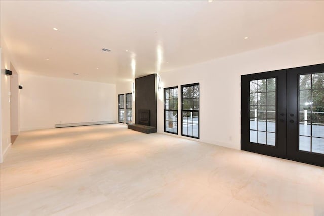 empty room with a large fireplace, french doors, and a baseboard radiator