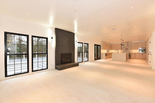 unfurnished living room featuring a large fireplace and sink