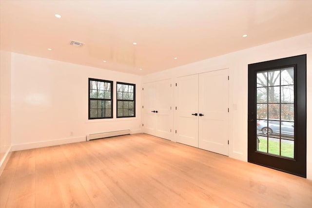 interior space featuring light hardwood / wood-style flooring, multiple windows, and a baseboard heating unit