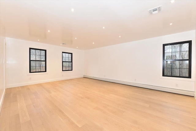 spare room with a baseboard heating unit and light wood-type flooring