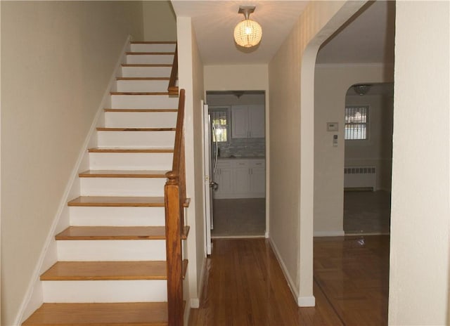 stairway with hardwood / wood-style floors, radiator, and ornamental molding