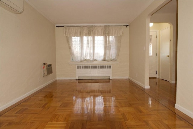 empty room with parquet floors, radiator heating unit, and a wall mounted AC