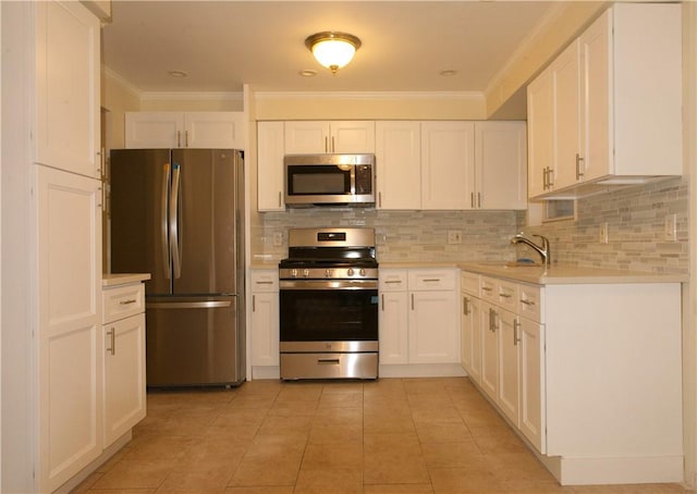 kitchen with backsplash, white cabinets, ornamental molding, appliances with stainless steel finishes, and light tile patterned flooring