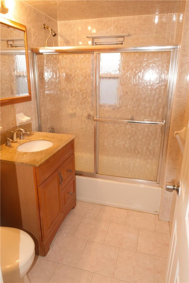 full bathroom featuring shower / bath combination with glass door, tile patterned flooring, vanity, and toilet