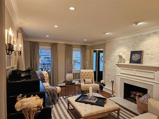 living room with hardwood / wood-style flooring, crown molding, a fireplace, and a baseboard radiator