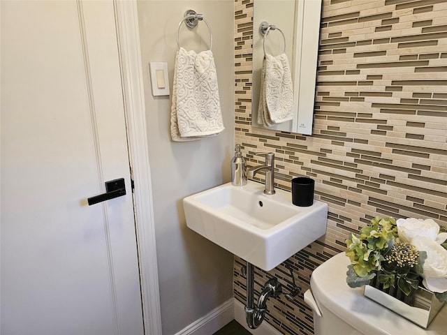 bathroom featuring tasteful backsplash, toilet, and sink