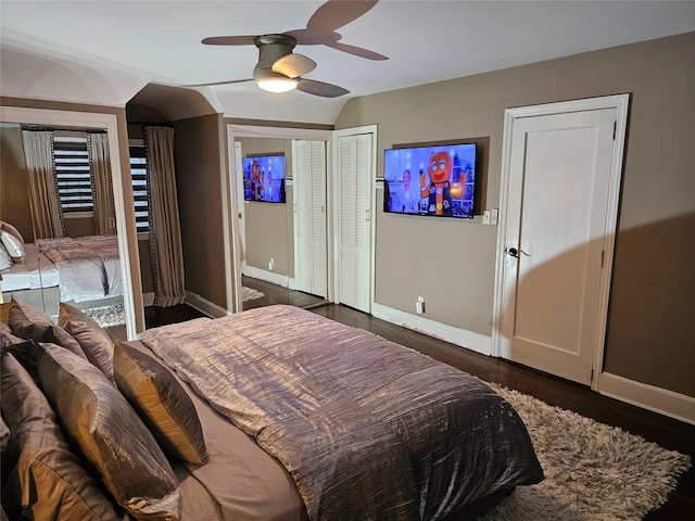 bedroom featuring multiple closets, ceiling fan, dark hardwood / wood-style flooring, and lofted ceiling