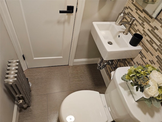 bathroom featuring decorative backsplash, radiator heating unit, toilet, and sink