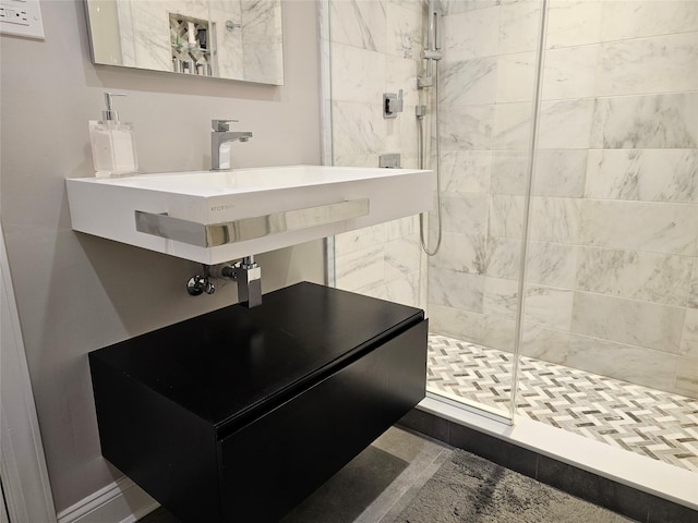 bathroom featuring a shower with shower door and sink