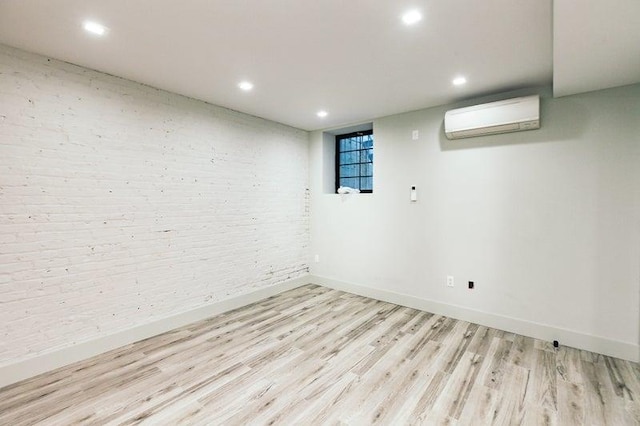 basement with light wood-style floors, recessed lighting, a wall unit AC, and baseboards