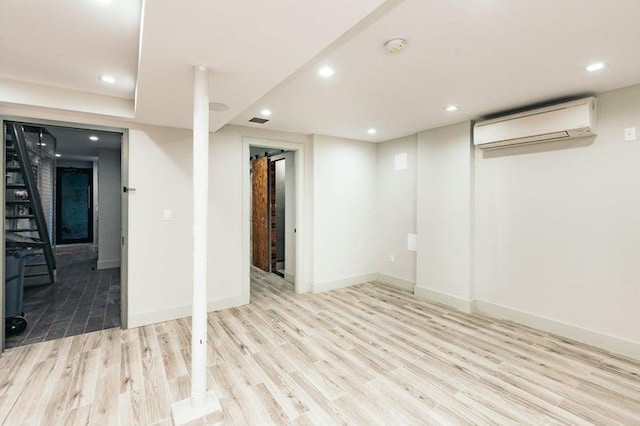 finished below grade area featuring recessed lighting, baseboards, wood finished floors, and a wall mounted AC