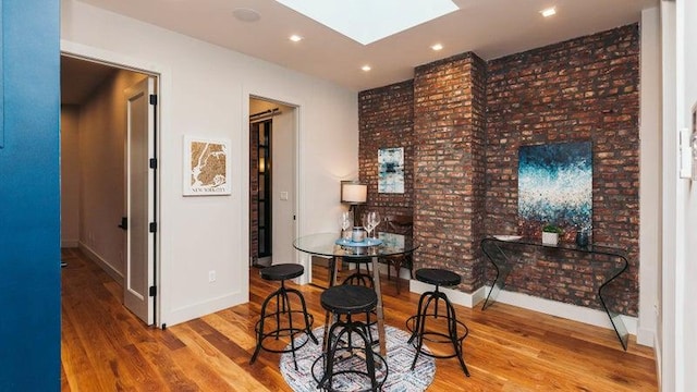 dining space featuring a skylight, baseboards, recessed lighting, and wood finished floors