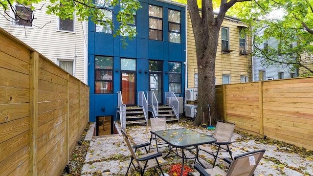 back of property with outdoor dining space and a fenced backyard