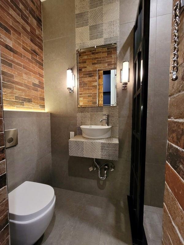 bathroom with toilet, tile walls, and a sink