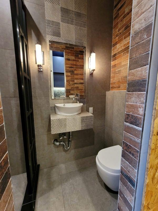 bathroom with toilet, tile patterned flooring, a sink, and tile walls